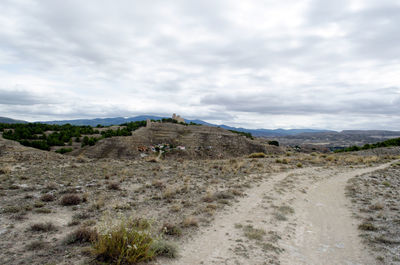 Dirt road passing through cloudy sky