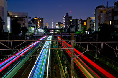 High angle view of light trails amidst buildings in city at night