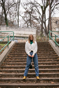 Portrait of young woman standing on staircase