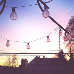 Low angle view of light bulbs hanging against sky