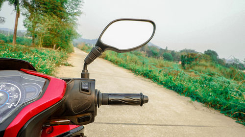 Motorcycle on road amidst field against sky