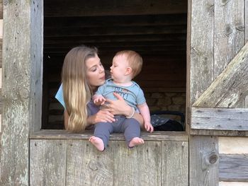 Full length of mother and daughter sitting on wood