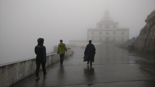 Rear view of people walking in front of foggy weather