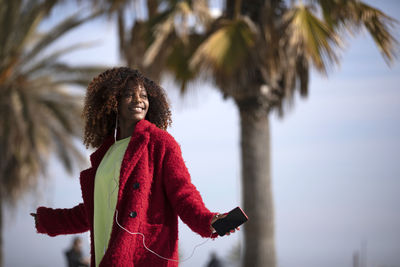 Side view of woman standing against palm tree