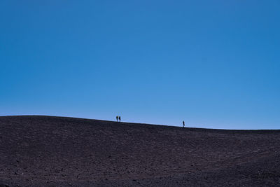 People on desert against clear blue sky