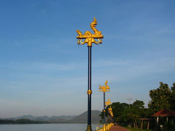 Low angle view of yellow statue against sky