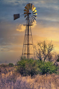 Traditional windmill on field against sky during sunset