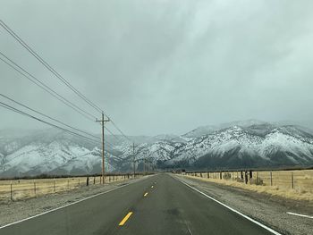 Road by snowcapped mountains against sky