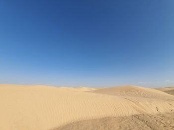 Scenic view of desert against clear blue sky