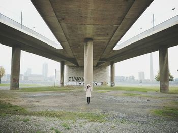 Woman standing below bridge