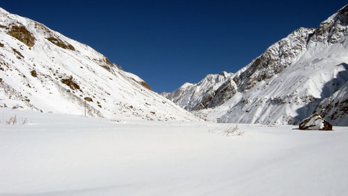 Scenic view of snowcapped mountains against clear blue sky