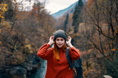 Woman wearing hat standing against trees during winter