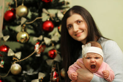 Portrait of baby and mother with christmas tree