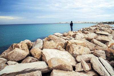 Rocks standing on rock by sea against sky