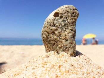 Close-up of rock on beach against clear sky