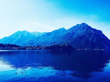 Scenic view of lake and mountains against blue sky