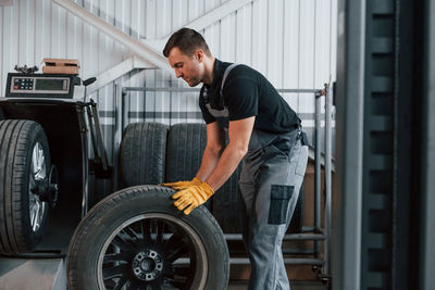 Working with broken wheel. man in uniform is working in the auto service.