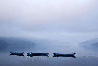 Nautical vessels moored on sea against sky