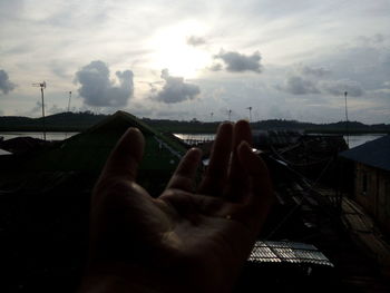 Low angle view of cropped hand against sky