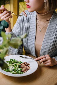 Midsection of woman eating food at table