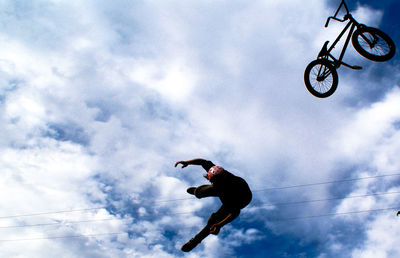 Low angle view of man jumping on cable against sky