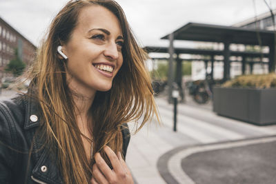 Smiling young woman wearing in-ear phones