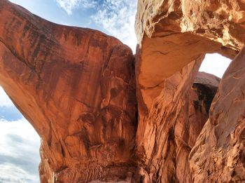 Low angle view of red rock against cloudy sky