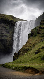 Scenic view of waterfall against sky - skogafoss