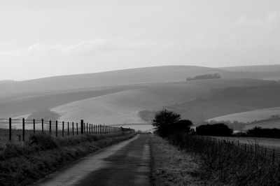 Road amidst field against sky