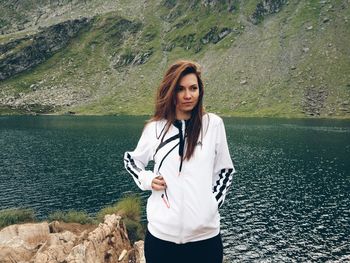 Beautiful woman standing at riverbank against mountain