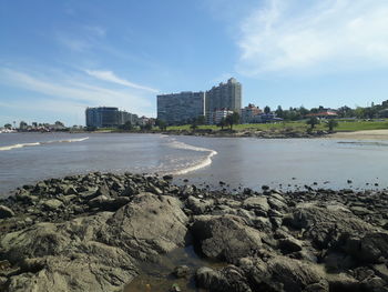 Scenic view of beach by city against sky