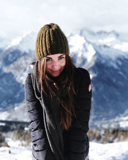 Portrait of smiling young woman standing on snow covered mountain