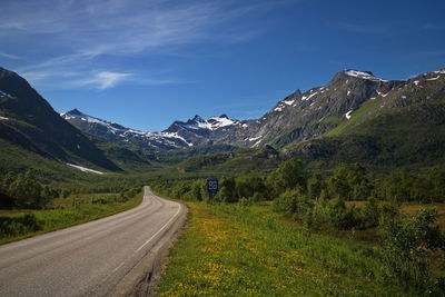 Road leading towards mountains against sky