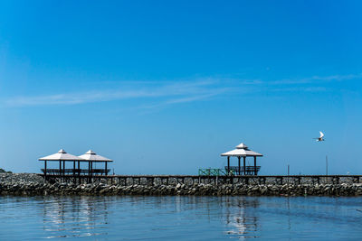 View of swimming pool by sea against blue sky