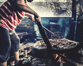 Midsection of man preparing food on fire pit