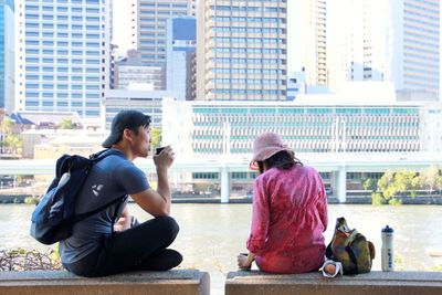 Rear view of man and woman sitting on city street