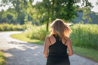 Rear view of young woman walking on road