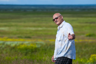 Portrait of man standing on field against sky