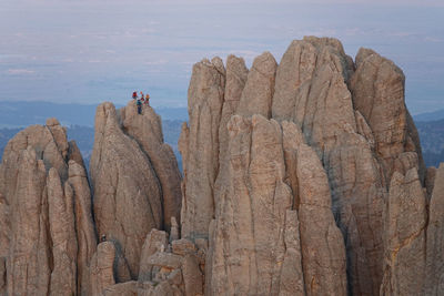 View of rock climbers and mountain goat near top of rock formations in custer state park at sunset