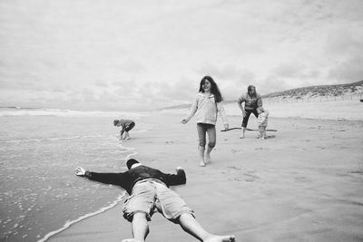 Children playing on beach against sky