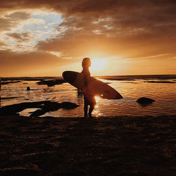 Woman on beach against sky during sunset