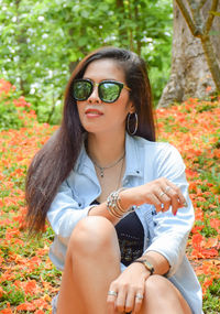 Mid adult woman wearing sunglasses while sitting on field in park