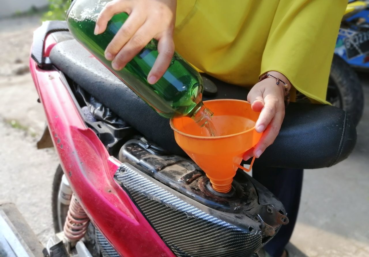 one person, adult, holding, yellow, food and drink, vehicle, lifestyles, women, drink, hand, midsection, day, refreshment, outdoors, close-up, casual clothing, wheel, leisure activity