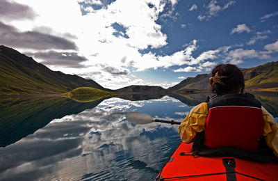 Woman rowing sea kayak on still lake in central iceland