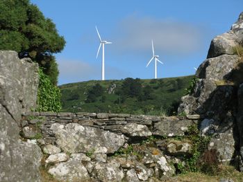 Windmill on farm by old ruins against sky