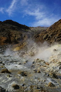 Geothermal landscape against cloudy sky at seltun