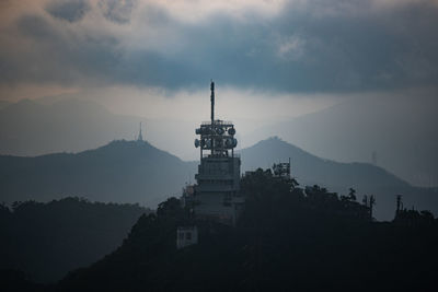 Silhouette of building and mountains against sky at sunset