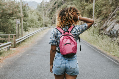 Young pretty girl with suitcase walking along the road