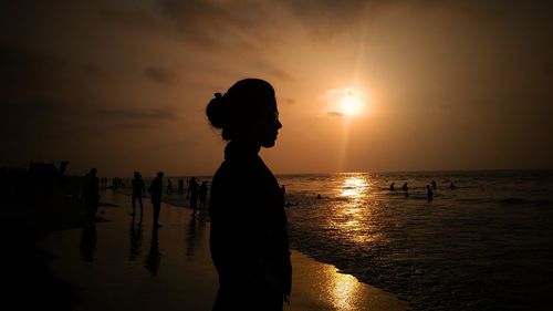 Side view of silhouette woman standing at beach during sunset