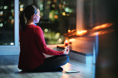 Side view of woman sitting on illuminated stage